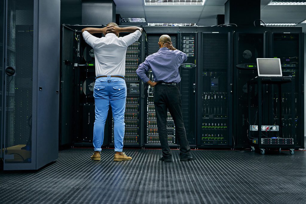 Two employees standing in server room upset by IT disaster.