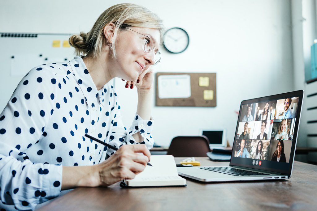 Smiling woman on Googles video call conference with her remote team. 