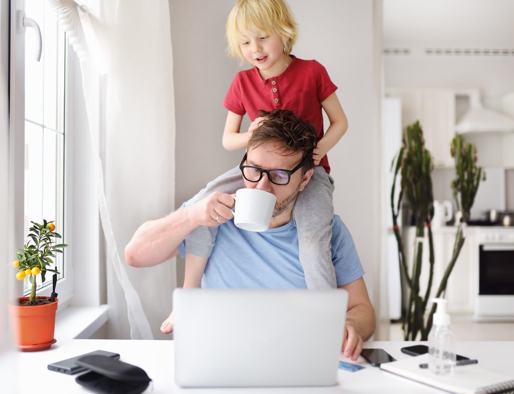 Man with child on shoulders accessing meeting from home.