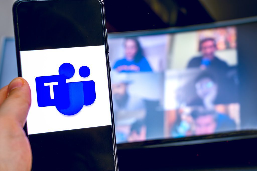 Microsoft Teams logo visible on device with virtual meeting on laptop in background