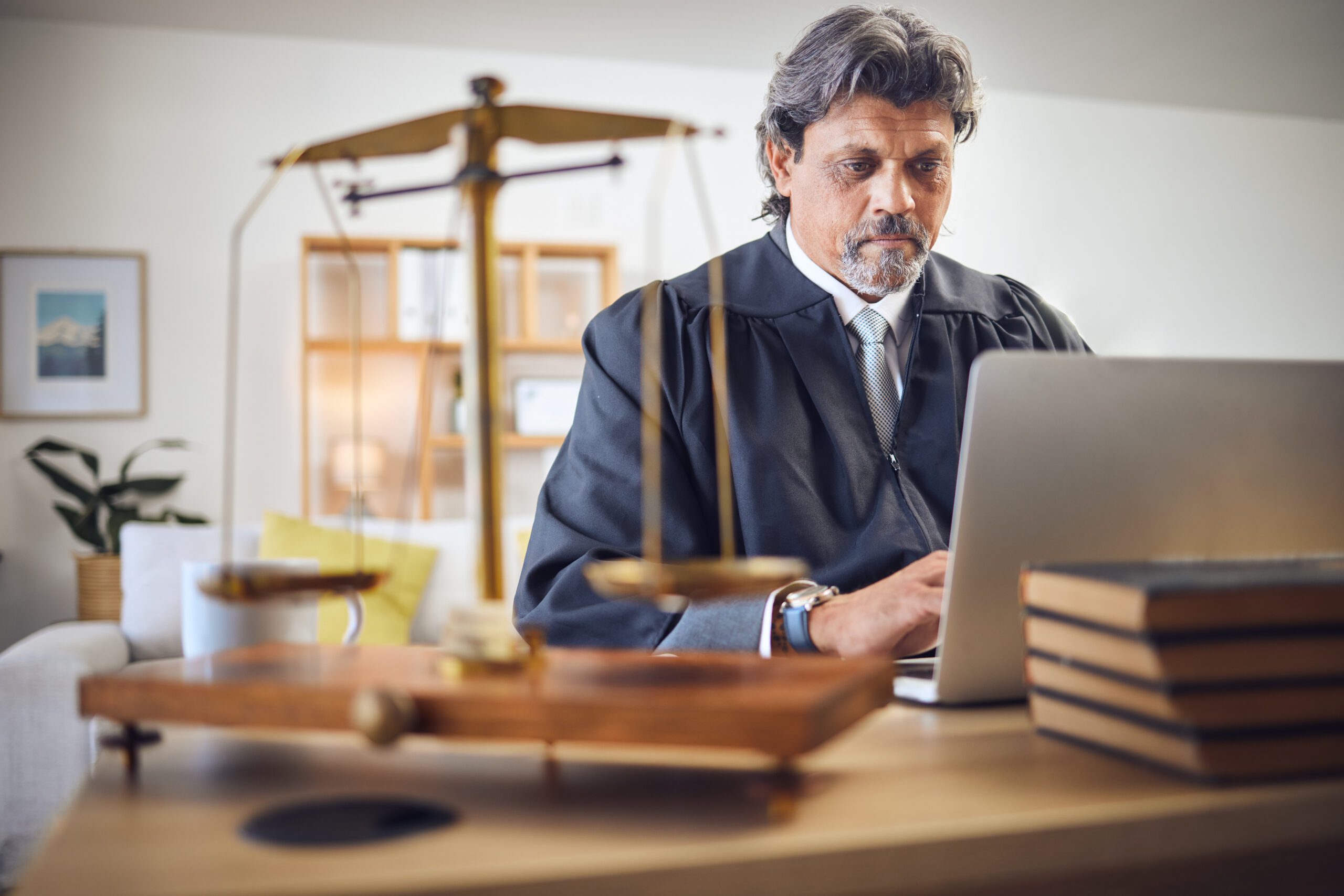 Male judge sitting at his laptop using virtual conferencing technology for court