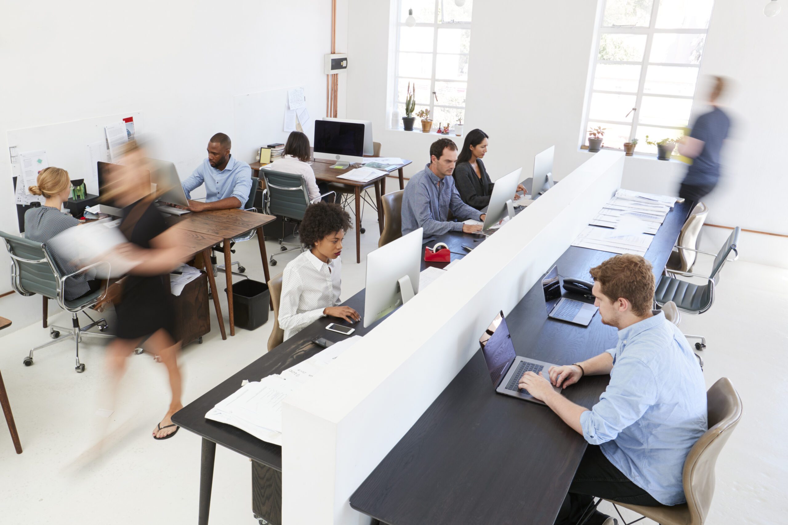 team of young colleagues working in an open-plan office that utilizes hot desking