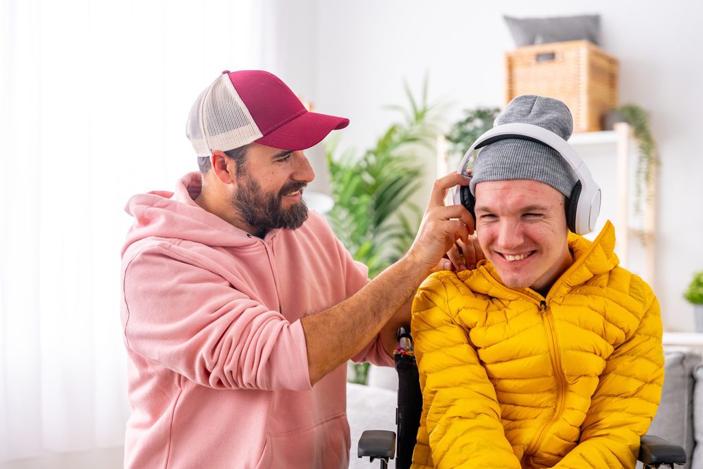 Parent putting headphones on student with disability in virtual classroom at home