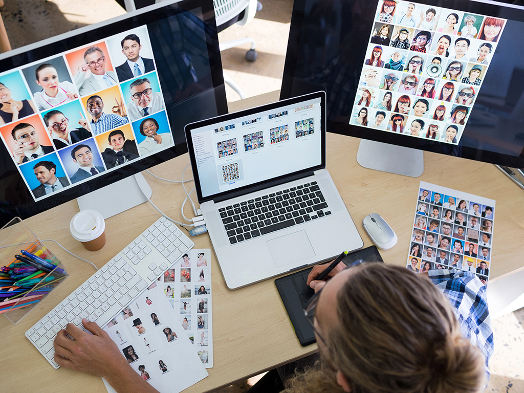 A hybrid work meeting between colleagues in different locations, including a young man who's dialing in from his own laptop.